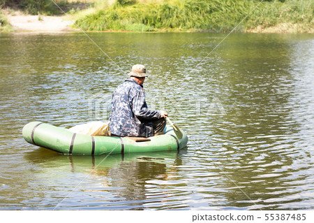 Fisherman on a rubber boat fishing on the river. Fisherman on a rubber boat fishing on the river. 55387485