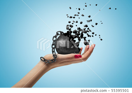 Closeup of woman's hand facing up and holding black wall and chain dissolving into pieces, on light Closeup of woman's hand facing up and holding black wall and chain dissolving into pieces, on light 55395501