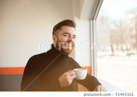 young businessman drinking coffee sitting at cafe  55403102