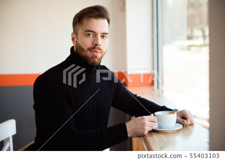 young businessman drinking coffee sitting at cafe  55403103