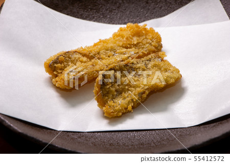 A fried tuna fish placed on a tempura sheeting paper. 55412572