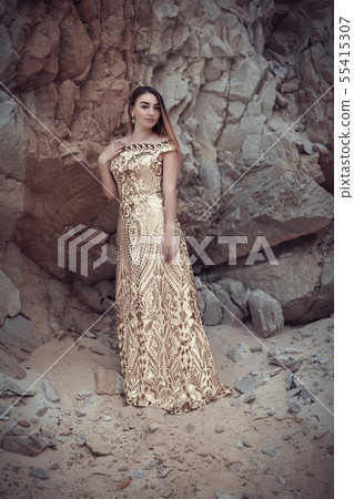 Girl in a golden dress on a background of rocks 55415307