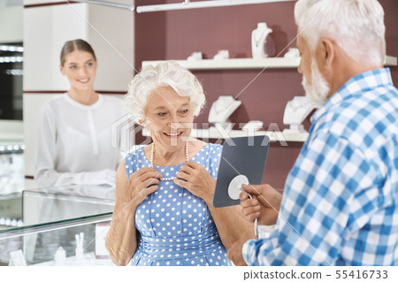Happy aged woman choosing luxury pearl necklace at store 55416733