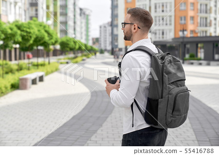 Young man walking with backpack and coffee cup in city. Young man walking with backpack and coffee cup in city. 55416788