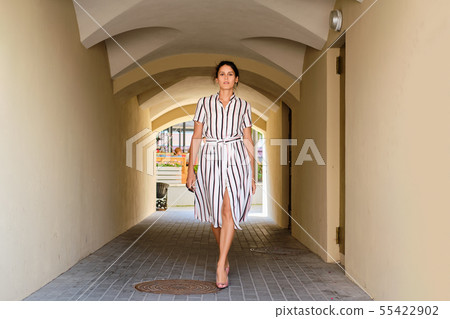 Pretty lady in striped dress walking in arch 55422902