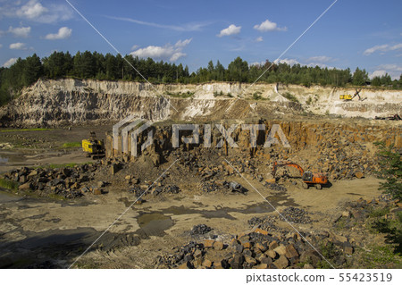 Excavator and basalt columns rocks. Heavy industry Excavator and basalt columns rocks. Heavy industry 55423519