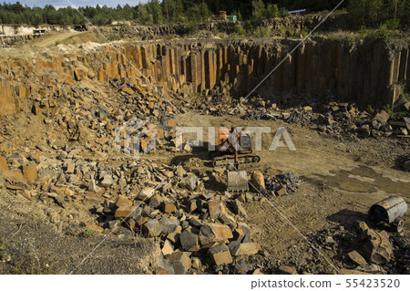Excavator and basalt columns rocks. Heavy industry Excavator and basalt columns rocks. Heavy industry 55423520