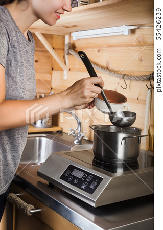 A Young Girl Cooks Soup On An Electric Stove Stock Photo