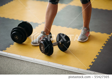 Fitness equipment two dumbbell near female foot on 55427305