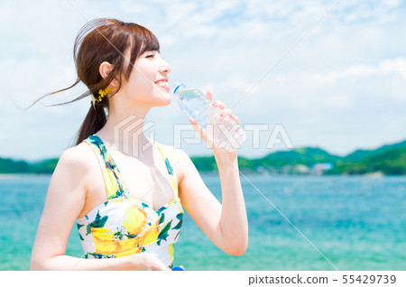 Young woman drinking water at the sea 55429739