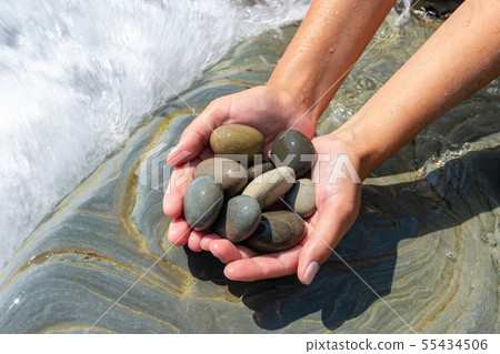 Palms hold a pile of stones on the seashore 55434506