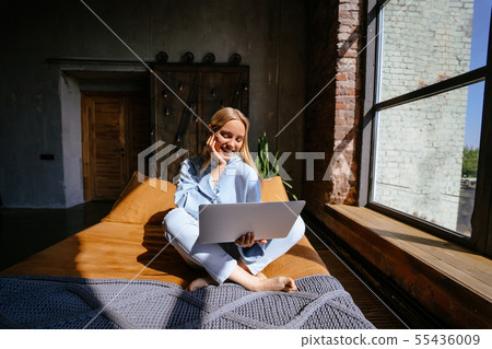Smiling attractive woman lying on bed using laptop 55436009