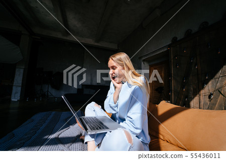 Smiling attractive woman lying on bed using laptop Smiling attractive woman lying on bed using laptop 55436011