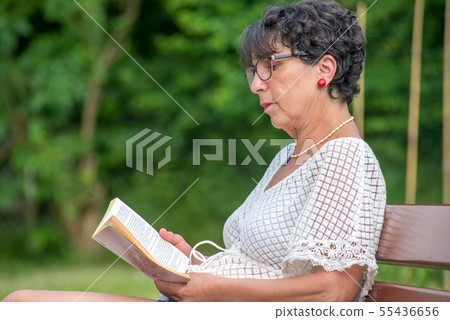 beautiful senior woman reading book in the garden 55436656