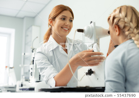 Red-haired ophthalmologist feeling joyful while examining girl 55437690