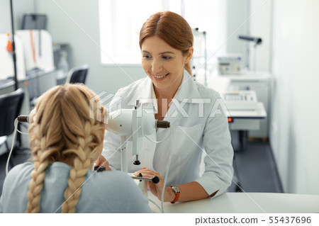 Red-haired ophthalmologist wearing white uniform examining girl 55437696