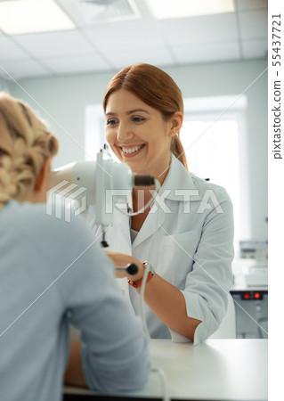 Eye doctor laughing while talking to girl during consultation Eye doctor laughing while talking to girl during consultation 55437721