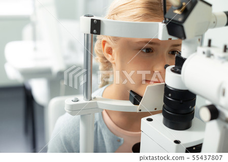 Girl looking into special glasses while having eye sight consultation Girl looking into special glasses while having eye sight consultation 55437807
