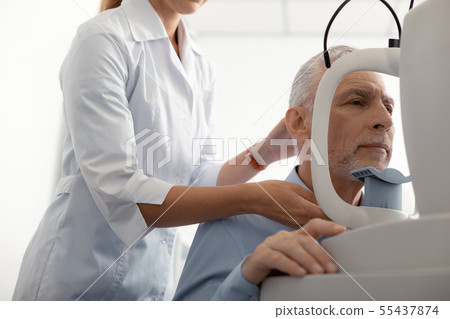 Ophthalmologist standing near patient while monitoring eye sight 55437874