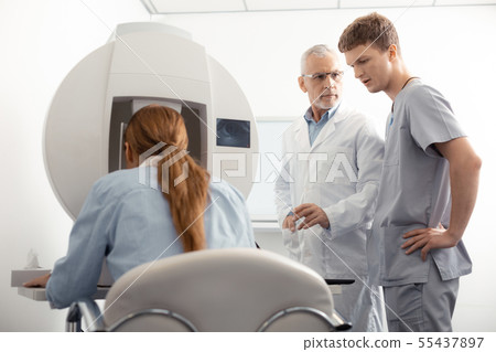 Dark-haired ophthalmologist trainee talking to professional doctor Dark-haired ophthalmologist trainee talking to professional doctor 55437897