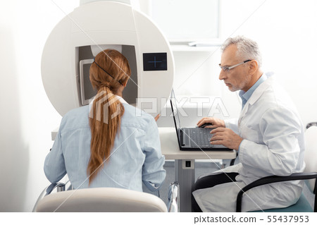 Red-haired woman wearing blue shirt visiting eye specialist 55437953