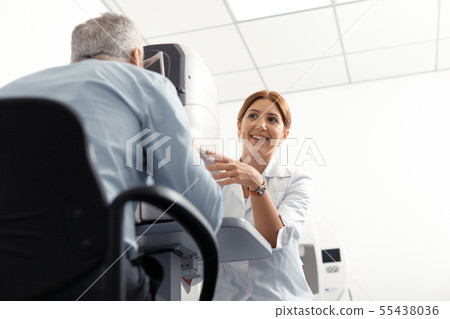 Beautiful young eye doctor smiling while examining retired man 55438036