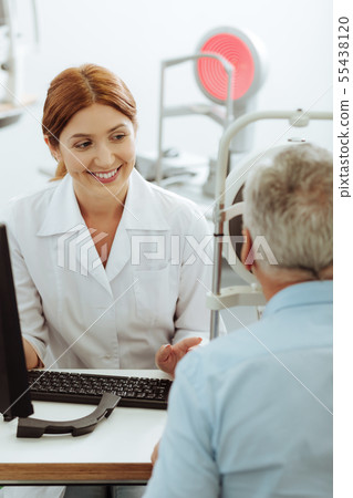 Smiling eye specialist feeling good while consulting retired man 55438120