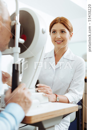 Red-haired beaming ophthalmologist feeling good while working Red-haired beaming ophthalmologist feeling good while working 55438220
