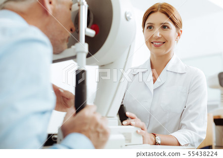 Red-haired smiling eye doctor enjoying the process of work Red-haired smiling eye doctor enjoying the process of work 55438224