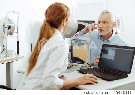 Dark-eyed patient speaking about the pain in his eye to doctor 55438311