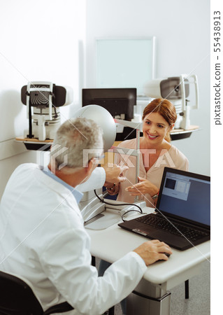 Patient of private eye clinic smiling while talking to doctor Patient of private eye clinic smiling while talking to doctor 55438913