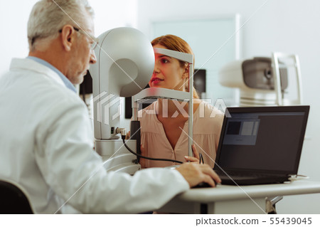 Experienced eye doctor examining young woman 55439045