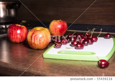Apples and cherries on a cutting board. 55439118