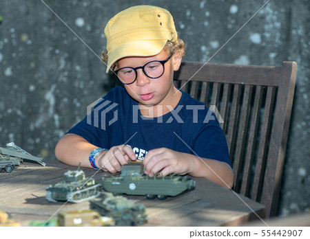 little boy with a yellow cap plays with toys 55442907