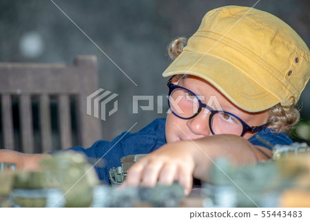 little boy with a yellow cap plays with toys 55443483