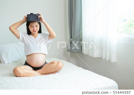 Pregnant Asian woman is wearing a Virtual Reality Pregnant Asian woman is wearing a Virtual Reality 55444397