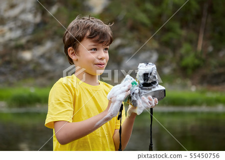 Boy is washing digital camera. 55450756