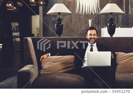 Handsome man looking relaxed and sitting on the sofa with laptop 55451270