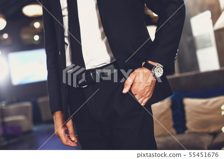 Close up of young man putting hand into the pocket of his trousers 55451676