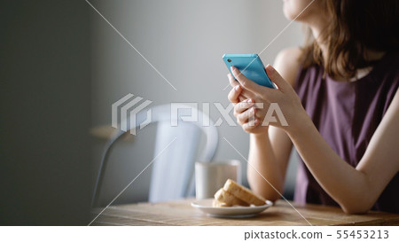 A woman watching a smartphone at a cafe 55453213