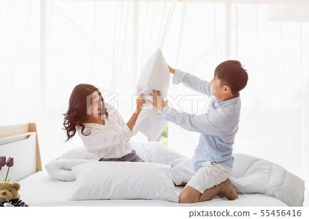 Asian couple sits on bed, They have pillow fight.. Asian couple sits on bed, They have pillow fight.. 55456416