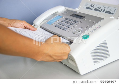 hand man are using a fax machine in the office 55456497