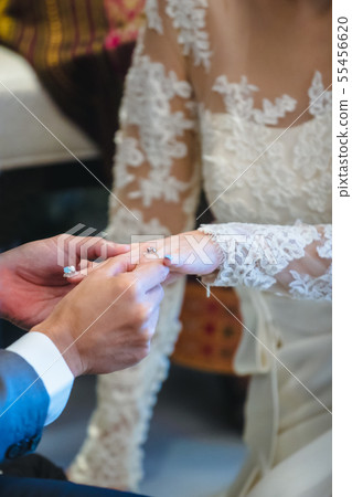 Groom wearing ring to bride in wedding ceremony.. 55456620