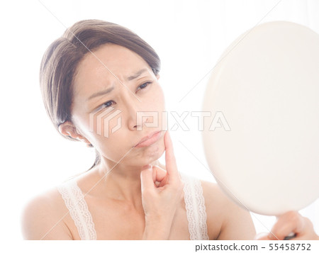 A woman troubled watching a mirror 55458752