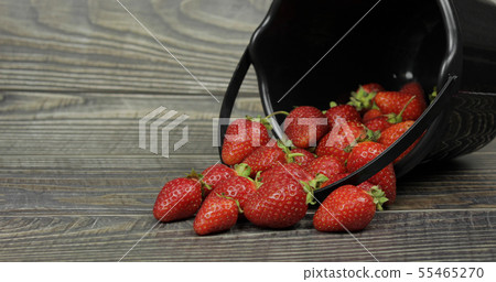 Strawberries in small black bucket on wooden table. Place for your logo or text 55465270
