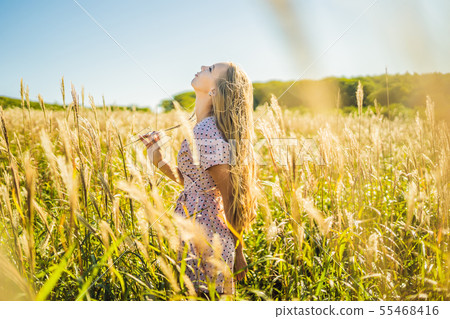 Young beautiful woman in autumn landscape with dry flowers, wheat spikes. Fashion autumn, winter 55468416