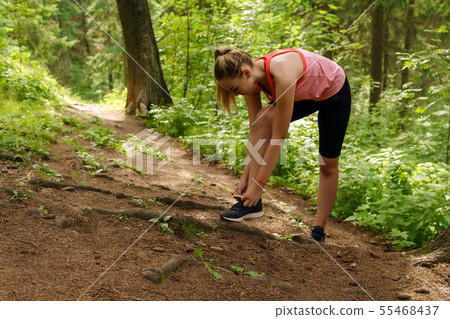 woman stopped jogging in a mountain forest to tie 55468437