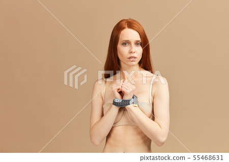 Red-haired female with a measuring tape around her wrists used as handcuffs Red-haired female with a measuring tape around her wrists used as handcuffs 55468631
