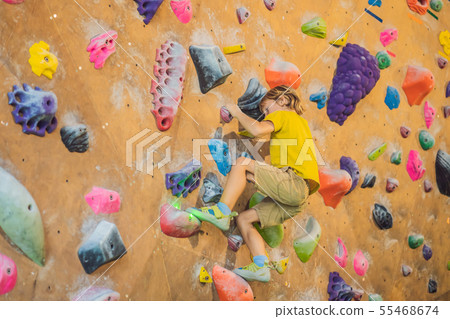 little boy climbing a rock wall in special boots. indoor 55468674