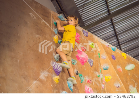 little boy climbing a rock wall in special boots. indoor 55468792